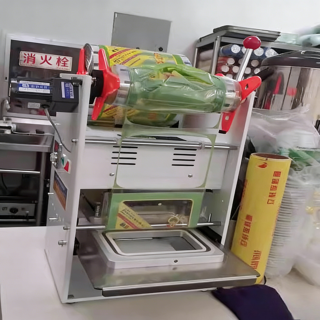 Lidding film reel and tray mold on a compact tray sealing machine